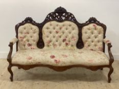 A Victorian walnut framed canope sofa, the floral carved crest rail over button back, open arms