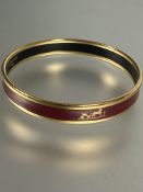 A gilt metal an dark rouge enamel stiff bangle with Groom a L'attante, made in Austria Hermes Paris,