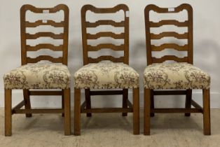 A set of three Late 19th / early 20th century oak framed ladder back dining chairs, with upholstered