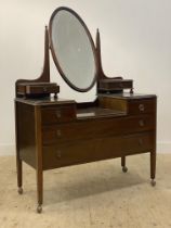 An Edwardian mahogany dressing chest, the bevelled oval mirror swivelling between two tapered posts,