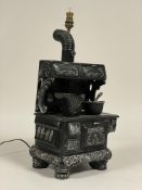 An unusual ceramic table lamp in the form of a 19th century stove, complete with cooking pot,