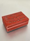 A 20thc Chinese red lacquered box and cover, the relief carved top with three figures in a