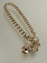 A 9ct gold kerb link chain bracelet with pig and heart charms and ring fastening, (D x 8 cm). 15.5g