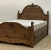 A pine queen size bed, the arched head and foot board with scroll carving and turned finals over