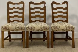 A set of three Late 19th / early 20th century oak framed ladder back dining chairs, with upholstered
