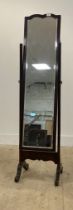 An Edwardian mahogany cheval mirror, the bevelled plate swivelling between square tapered uprights