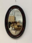 An early 20th century simulated rosewood framed oval wall mirror with bevelled edge 82cm x 55cm.