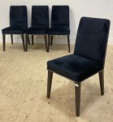 A set of four contemporary dining chairs, each upholstered in studded black velvet, raised on square