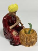 A Staffordshire china figure of a snake charmer decorated with polychrome enamels, (H x 13 cm X W