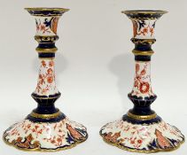 A pair of Royal Crown Derby Imari palette candlestick holders decorated with red transfer printed fl