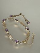 A 9ct gold Celtic knot line style bracelet set five oval amethysts in rub over setting with safety
