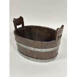 A 1920's oak coopered two handled tub or wine cooler of oval form with twin handles to sides bound