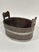 A 1920's oak coopered two handled tub or wine cooler of oval form with twin handles to sides bound