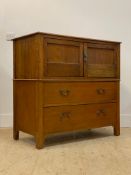 An early 20th century oak side cabinet, the twin panelled doors above two drawers to base, raised on
