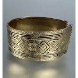 A Middle Eastern yellow metal engraved cuff style hinged bangle with traces of black enamel, a/f.