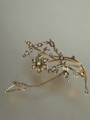 A Edwardian 9ct gold floral spray brooch set seed pearls complete with safety chain, (L x 6.5cm)