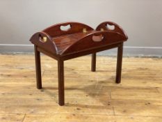 A mahogany campaign style butlers tray on stand coffee table, the panelled tray, of oval outline,