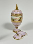 A 19thc continental porcelain lavender urn and cover, the diamond pierced top with gilt flame finial
