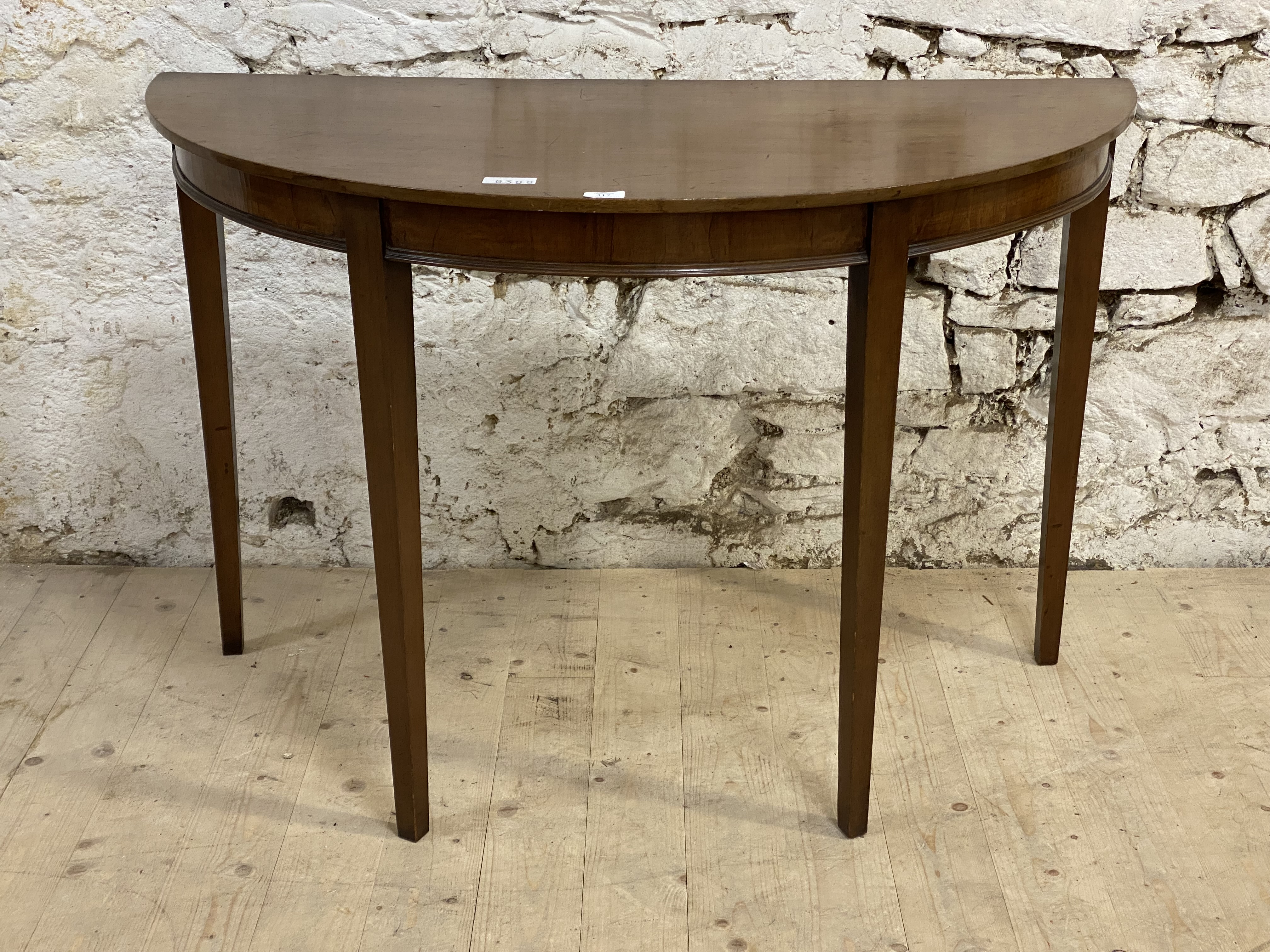 A George III style demi lune mahogany console table, early 20th century, the top over a figured