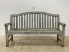 A silvered teak garden bench, with arched crest rail over slatted back and seat, raised on block