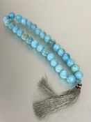A large turquoise dyed marble bead necklace joined with knot and twin tassels. (L x 40 cm  each bead