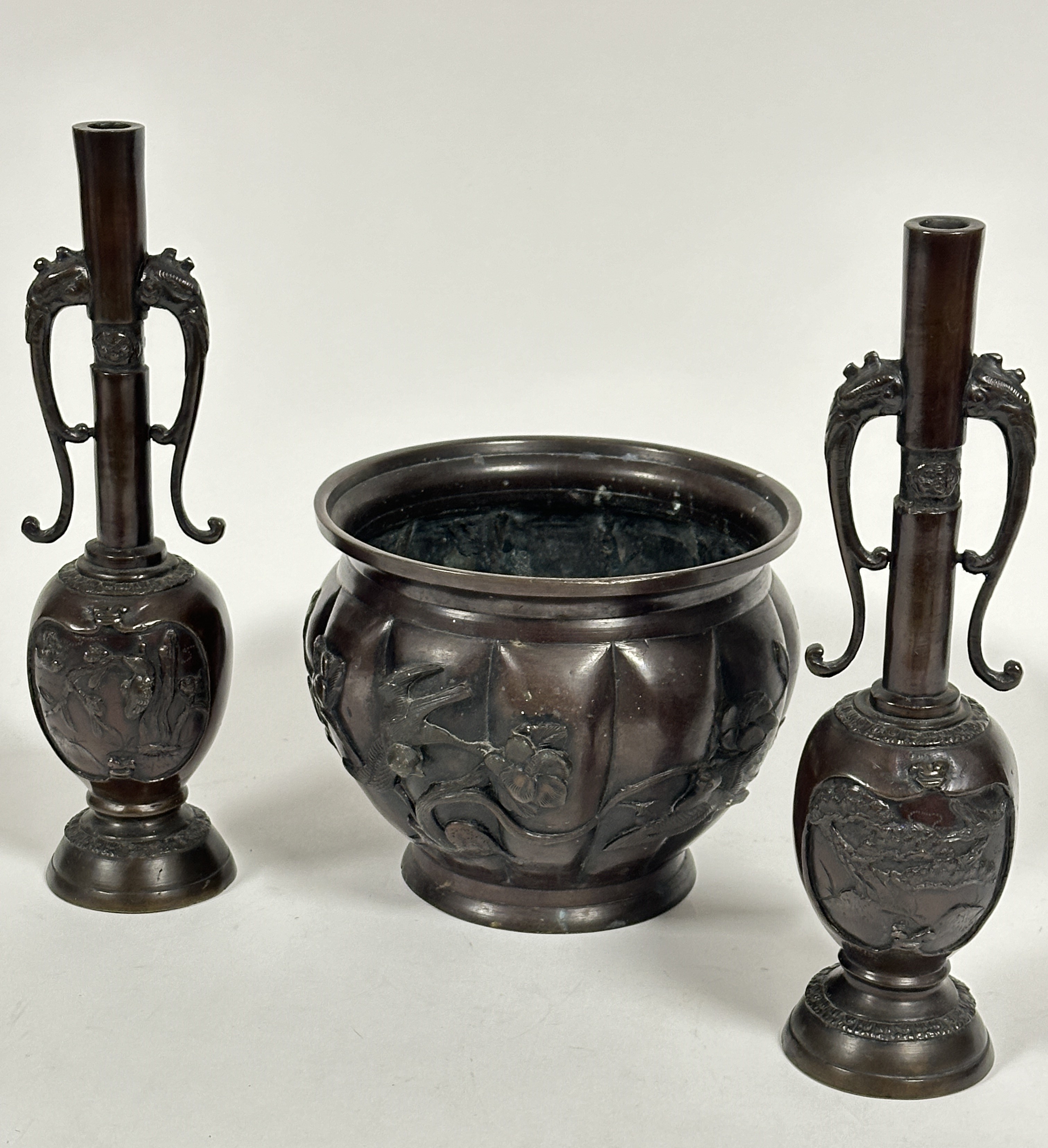 A Japanese patinated bronze jardiniere of paneled tapered design with cast bird and floral