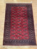 A hand knotted Turkmen Bokhara rug, the red ground with three rows of guls within a multi line