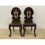 A pair of Victorian hall chairs, each with oval back pierced and carved in low relief with scrolls