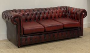 A Vintage Chesterfield three seat sofa, upholstered in deep buttoned ox blood leather, moving on