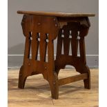 An Arts and Crafts period walnut stool, the top with moulded edge raised on pierced panel end