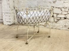 A Victorian white painted wrought and cast iron cot, moving on ceramic castors. H86cm