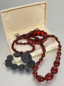A 1920s -30s dark amber coloured bead necklace with screw fastening, ( L x 36 cm), a red amber
