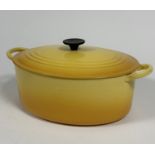 A Le Creuset oval cast iron casserole dish and cover with gradated yellow enamel finish, shows no