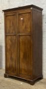An early 20th century mahogany wardrobe, the dentil cornice above two panelled doors enclosing