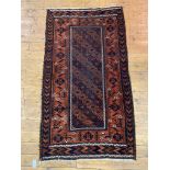 A hand knotted Baluchi rug of typical design and palette 177cm x 100cm