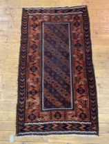A hand knotted Baluchi rug of typical design and palette 177cm x 100cm