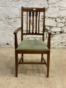 An Arts and Crafts period walnut, mahogany and beech elbow chair, with carved crest rail and spars