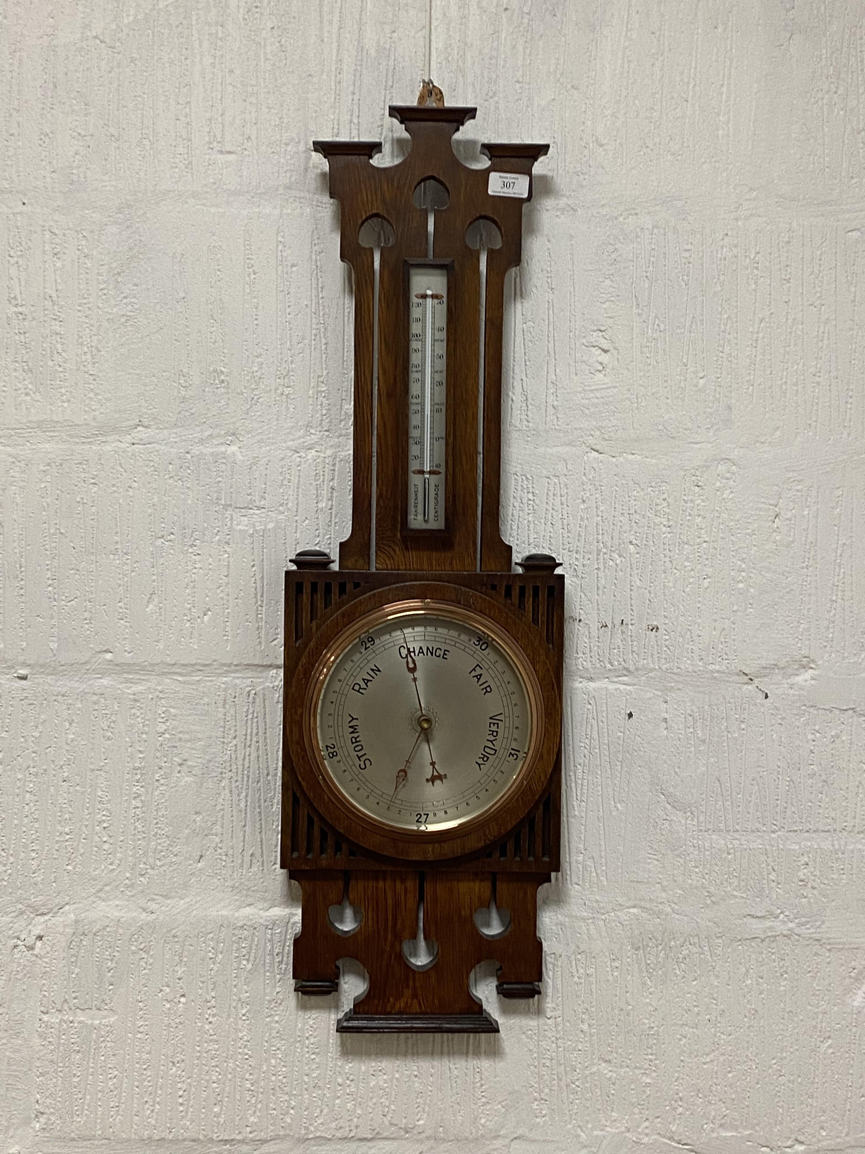 An Arts and Crafts pierce carved oak framed wall hanging aneroid barometer and thermometer, early