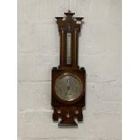 An Arts and Crafts pierce carved oak framed wall hanging aneroid barometer and thermometer, early