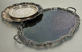 A Epns oval scalloped two handled drink tray, (L x 60 cm), an Epns circular engraved scalloped tray,