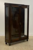 An early 20th century glazed oak two door display cabinet or bookcase, the interior fitted with