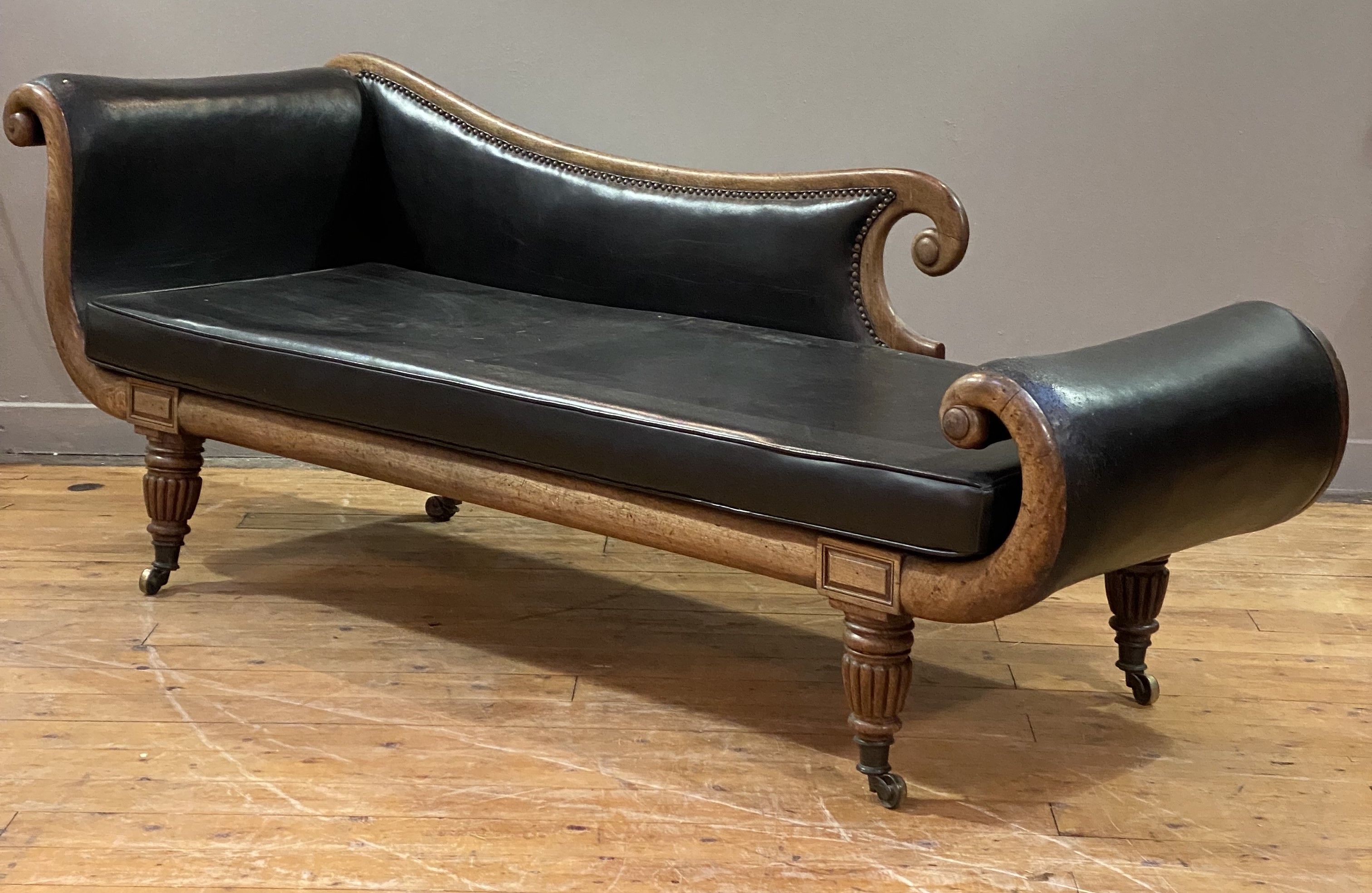 A late Regency mahogany-framed chaise longue, the scrolling show frame with squab cushion