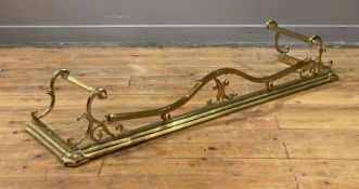 An Art Nouveau period gilt brass fire fender, the frame, of scrolling form, on a stepped base.