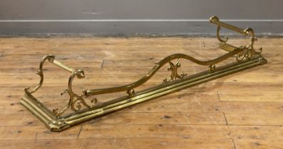 An Art Nouveau period gilt brass fire fender, the frame, of scrolling form, on a stepped base.