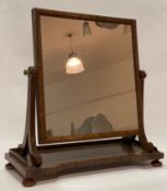 A mid 19th century mahogany swing mirror, the rectangular plate swivelling between two scrolling