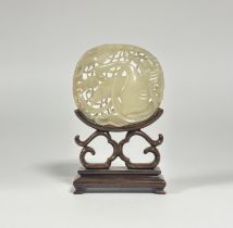 A Chinese carved jadeite plaque, of pale celadon colour, pierced and carved with a goose amidst lily