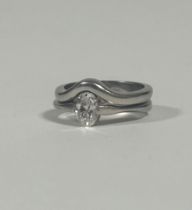 A platinum solitaire diamond ring with platinum wedding band en suite