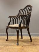 An Edwardian mahogany elbow chair, the undulating crest rail and swept arms on a gallery formed as