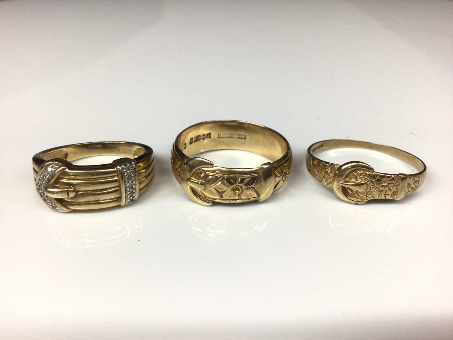 9ct gold diamond set buckle ring and two other 9ct gold buckle rings with embossed floral decoration