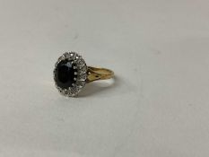 9ct gold Sapphire and diamond cluster ring with an oval mixed cut dark blue sapphire surrounded by a